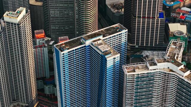 Drone tilts above Ayala Avenue revealing dense Makati skyscrapers at sunset