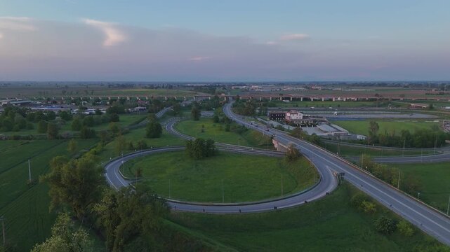 A1 Autostrada del Sole and A21 motorway junction near Fiorenzuola d&rsquo;Arda, Piacenza, Po Valley, Italy, drone pan right aerial shot above toll infrastructure, SS9 Via Emilia corridor,