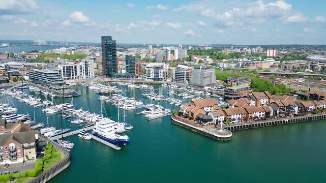 Drone view of Southampton marina with luxury yachts, waterfront buildings, and modern urban skyline beside the coastal harbor in southern England