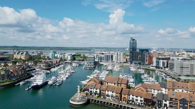 Drone aerial view of Southampton marina with waterfront apartments, luxury yachts, and modern skyline beside the coastal harbor in southern England