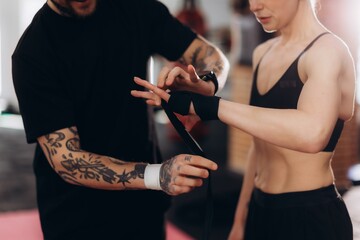 Trainer wrapping female fighter's hands for boxing training © Roman