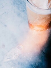 Fototapeta premium Light colored marble background with copy space next to a cold glass of iced coffee for cafe menu design, hospitality branding and summer beverage advertising