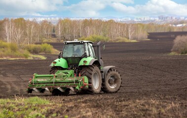 Fototapeta premium A tractor plowing a field in spring. Agricultural work, farming.