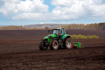 Fototapeta premium A tractor plowing a field in spring. Agriculture, farming.
