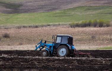 Fototapeta premium A tractor working in a field in spring. Agriculture, farming.