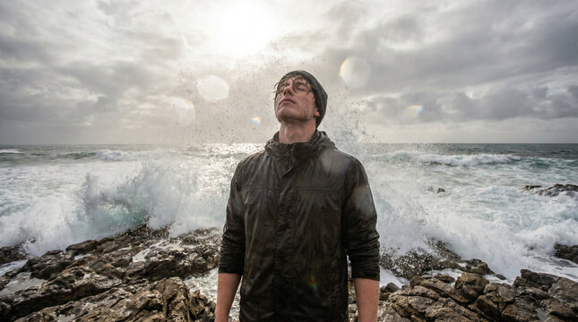 Dramatic Portrait of Man Standing in Crashing Ocean Waves and Stormy Sky