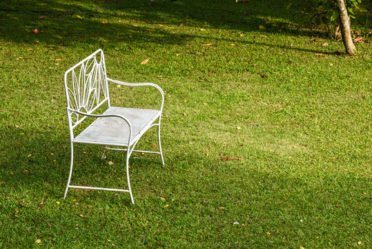 Vintage white metal garden chair on a lush green lawn in a peaceful backyard garden