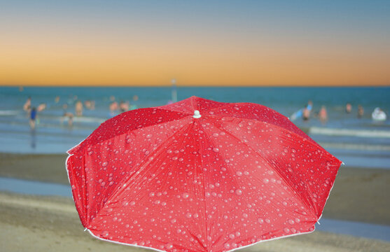 Open umbrellas on a deserted beach as the sun sets on the horizon