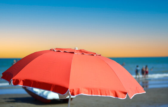 The setting sun paints the sky behind the open umbrellas