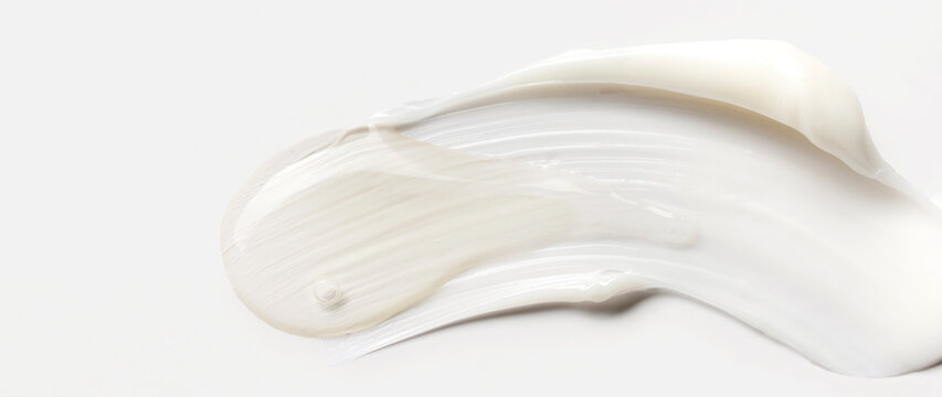 samples of cosmetic care products smear of cream and serum texture on a light background