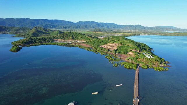 Aerial drone footage in Bungin most congested island in the world, with the connecting asphalt bridge, in blue water bay, Olet Sangenges moutain area in the back, Sumbawa island, Indonesia