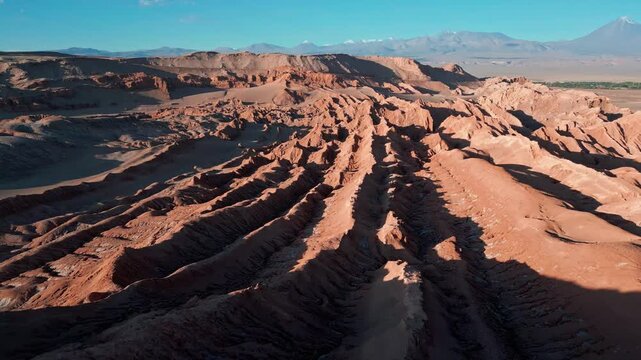 Tilting down over parallel salt ridges revealing deep grooves and layered erosion patterns across the ancient desert terrain. Valle de la Luna, Chile