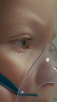 Vertical Screen: Close-up of a child using a mask connected to a nebulizer. The child inhales a saline solution to help with cough and respiratory issues at home.