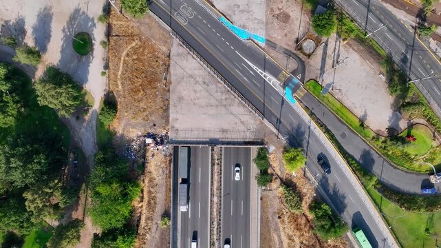 Bird's eye view over urban highway underpass with bus lane overpass bridge trees and cycle path creating a geometric multi level transport infrastructure pattern from directly above