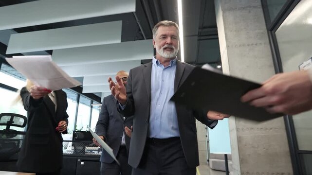Two men in suits discuss a tablet in a bright office