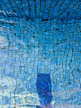 Blue Swimming Pool Water Ripples Over Mosaic Tiles in Morning Light