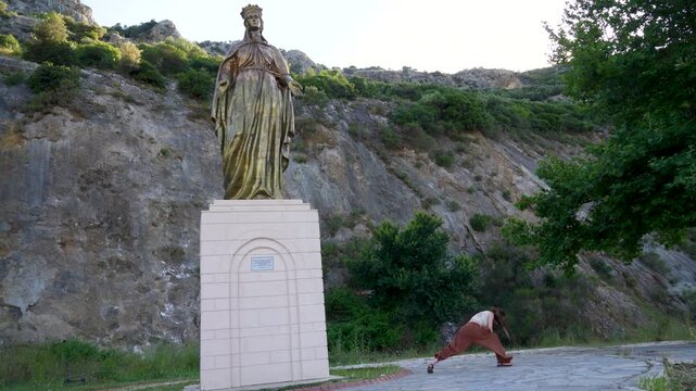 Woman practicing yoga near Virgin Mary statue in Izmir Turkey