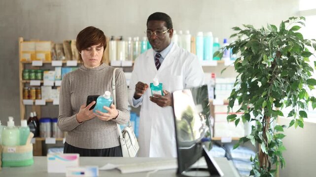Woman buyer scans mouthwash qr code with woman pharmacist. High quality 4k footage