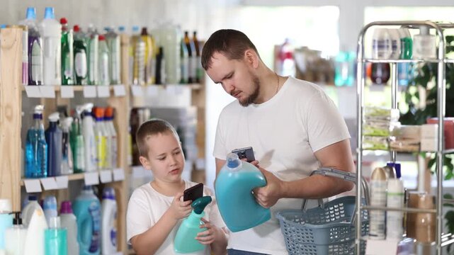 Young man with his son buyers scanning qr code for laundry detergent in household chemicals store