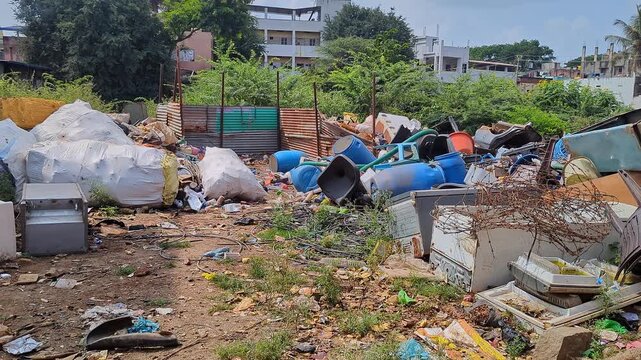 Wide view of urban waste storage with plastic and iron scrap items piled outdoors