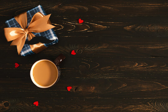Horizontal Flat Lay Banner of Plaid Gift Box with Gold Ribbon, Coffee Cup, Paper Mustache and Little Hearts on Dark Wooden Background with Copyspace, Father's Day or Birthday Concept