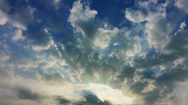 Cinematic sunbeams breaking through dramatic clouds in blue sky at sunrise