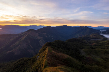 Fototapeta premium Landscape of Morning Mist with Mountain Layer. mountain ridge and clouds in rural jungle bush forest