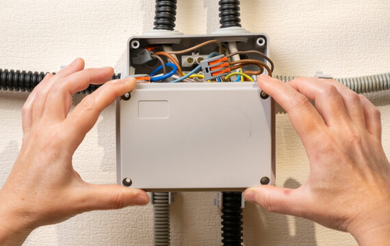 Work being done on electrical wiring inside a junction box in a home setting in the afternoon