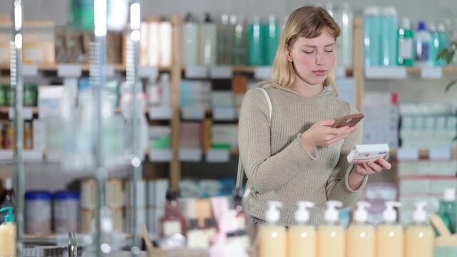 Young woman buyer scanning qr code for box of paracetamol tablets in pharmacy