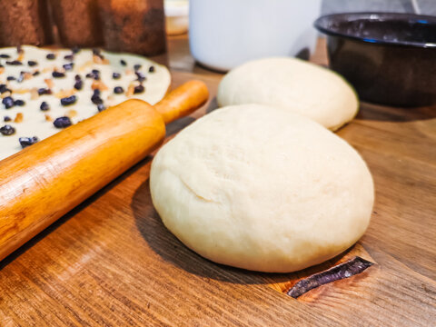 Raw Dough Balls, Wooden Rolling Pin and Rolled Out Dough Sprinkled with Raisins for making cruffins