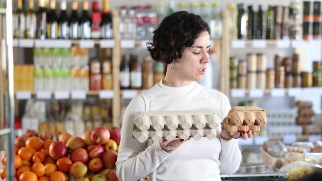 Adult woman buyer choosing packaged eggs in grocery store