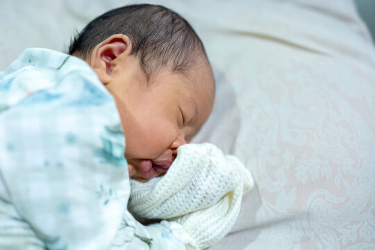 Side Profile of a Peaceful Newborn Baby Sleeping Softly on a Pillow with Hand in a Mitt