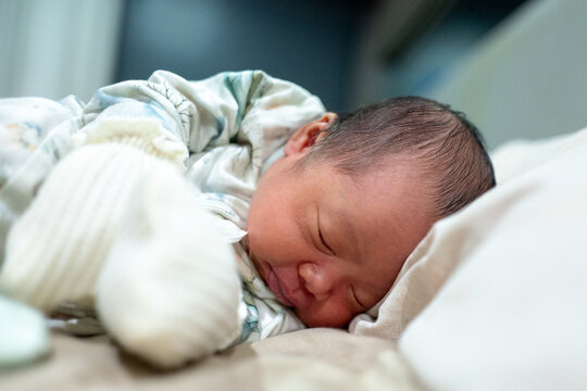 Adorable Newborn Baby Sleeping Peacefully on Tummy Wearing Scratch Mittens and Patterned Onesie