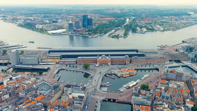 Amsterdam, Netherlands. Amsterdam Centraal Station, a Gothic and Renaissance Revival red-brick facade with twin towers, Drone footage over the IJ waterfront. Drone footage, Point of interest