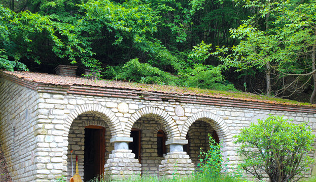 Living quarters for monks. White stone walls, tiled roof. Greenery in the background. Bodbe, Kakheti, Georgia