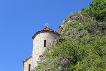 Fototapeta premium The dome of the church of the Elia Monastery at the foot of the cliff. The walls are made of light stone, the roof is tiled. Elia, Kakheti, Georgia