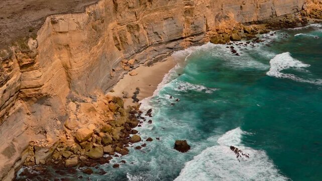 High aerial shot ekas reveals a secluded beach beneath rugged cliffs with turquoise water and rolling waves for tropical escape travel resort and coastal nature themes