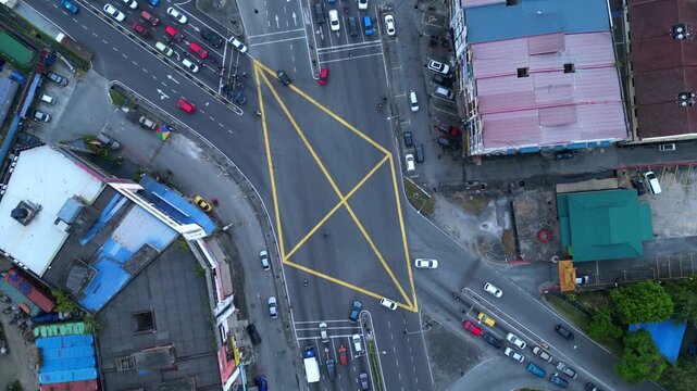 vertical bird's eye view, cars and motorbikes driving through a yellow marked box junction in Port Klang, Malaysia. Magic aerial view drone camera pointing down