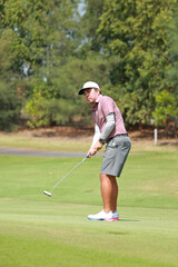 Obraz premium Happy Asian man Golfer Hitting Golf Shot on golf Course. teeing off golf ball. Sport outdoor