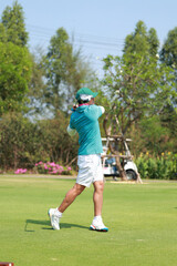 Obraz premium Happy Asian man Golfer Hitting Golf Shot on golf Course. teeing off golf ball. Sport outdoor