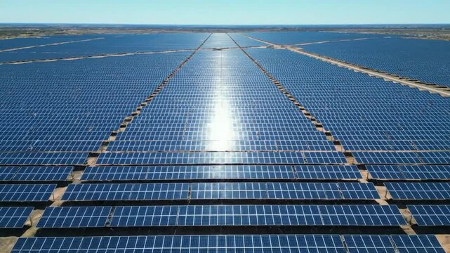 Aerial view of a massive solar farm, renewable energy infrastructure on a sunny day providing clean power to the grid.
