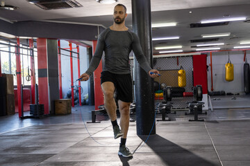 Indian man jumping rope, wearing long-sleeve fitted top and shorts at commercial gym © wavebreak3