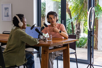 Obraz premium African American woman and Indian man cohosts recording podcast at home with mics and laptop