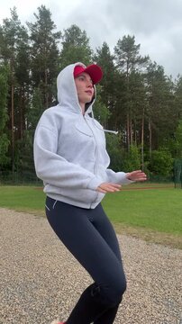 Side view of athletic female in sportswear practicing mindful movement and balance workout on gravel path against green trees