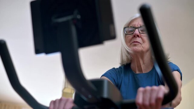 Older woman focused on a home workout using a stationary exercise bike  