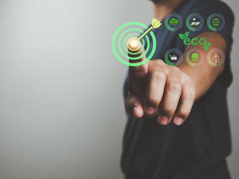 Eco target concept with finger pressing green bullseye and sustainability icons showing renewable energy, recycling, tree planting and low emission transport renewable energy