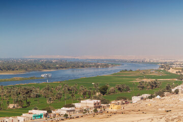Obraz premium View from above of the Nile river, in Middle Egypt, region of El-Minia with a cruise ship. On each bank of the sacred river, every square meter is used for agriculture.
