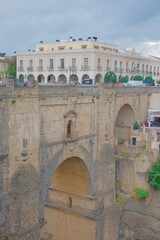 Fototapeta premium Close-up view of Puente Nuevo bridge stone arch structure with historic yellow building and town square — detailed 18th century masonry of iconic Ronda landmark, Andalusia, Spain