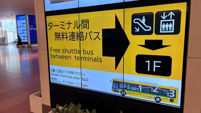 Haneda Airport (HND) Terminal 3 digital wayfinding sign with directions to the 1F floor free shuttle bus between terminals for passengers - Tokyo, Japan, June 6, 2025