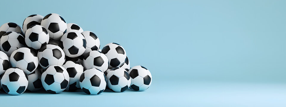 A large pile of football balls arranged against a blue studio background with space for text &ndash; a concept for sports equipment and a tournament banner